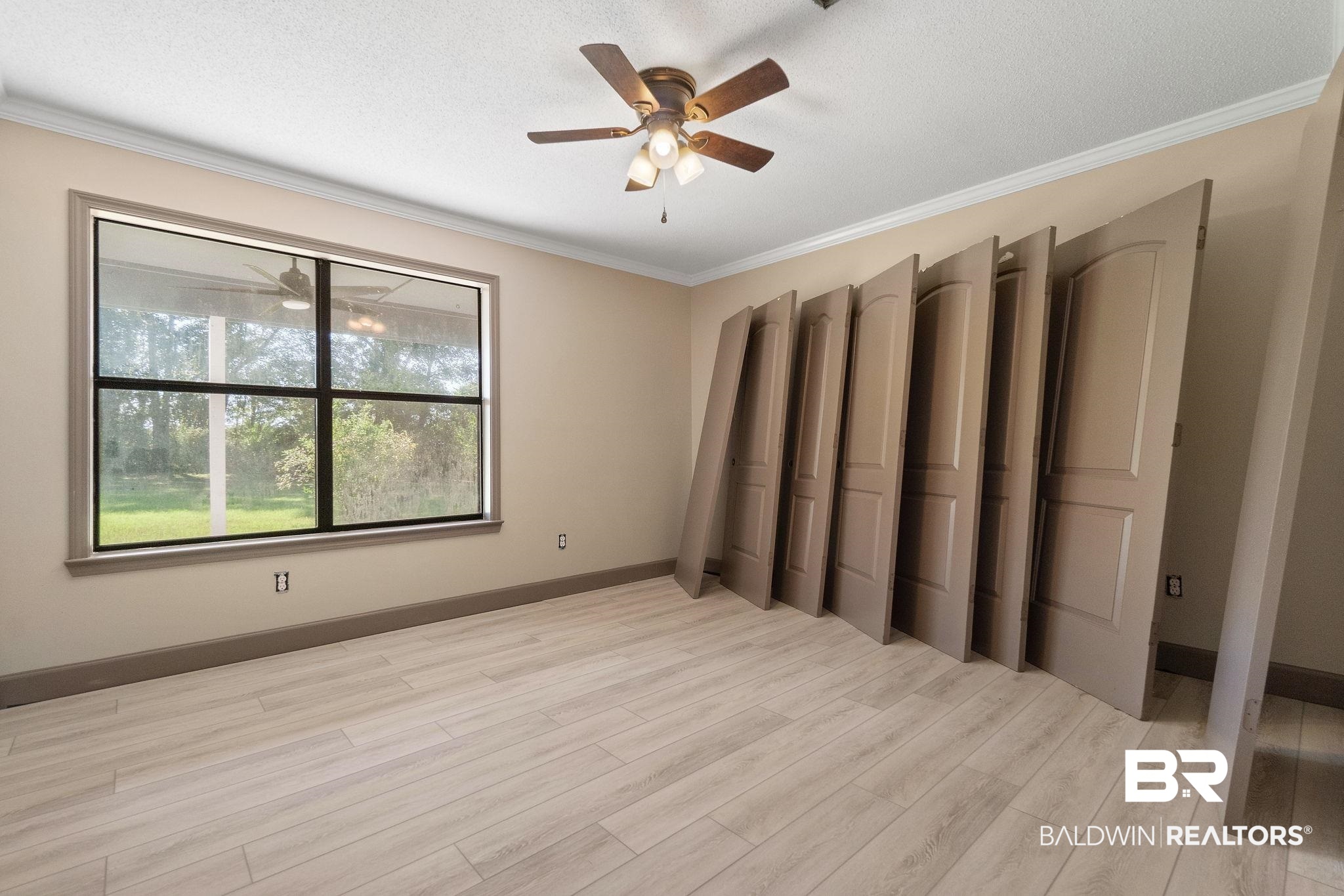 27300 C R Watson Road Robertsdale, AL 36567 - Photo 19 of 35 Unfurnished bedroom featuring a textured ceiling, crown molding, ceiling fan, and light hardwood / wood-style flooring