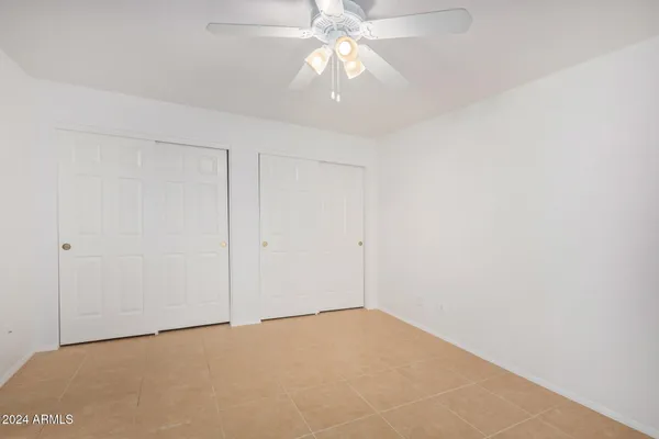 a view of an empty room and chandelier fan