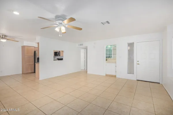 a view of an empty room and chandelier fan