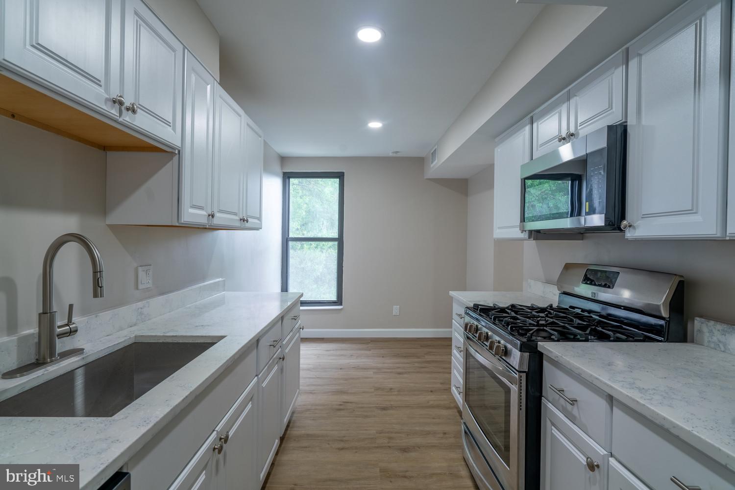 112 Duvall Lane, Unit 304 Gaithersburg, MD 20877 - Photo 12 of 27 a kitchen with stainless steel appliances a sink a stove cabinets and a kitchen island