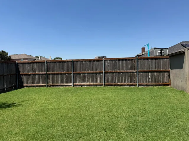 a view of a backyard with wooden fence