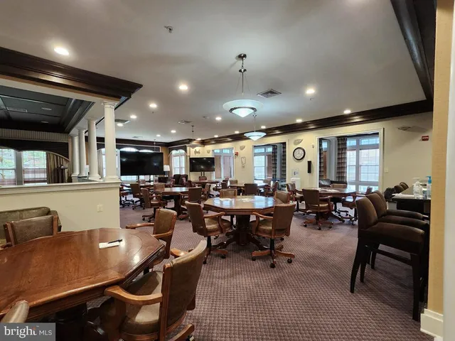 a living room with lots of chairs a desk and a flat screen tv