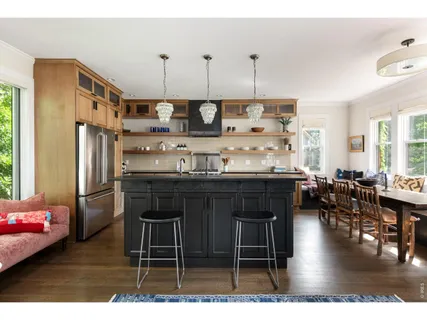 a kitchen with stainless steel appliances kitchen island granite countertop a table chairs and a refrigerator