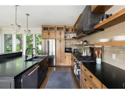 a kitchen with stainless steel appliances granite countertop a sink a stove and a refrigerator