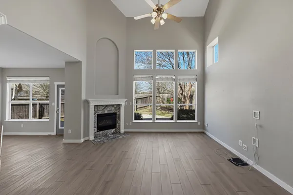 an empty room with wooden floor fireplace and windows