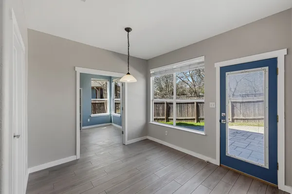 a view of an empty room with window and wooden floor