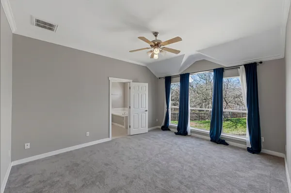 an empty room with a ceiling fan and a large window
