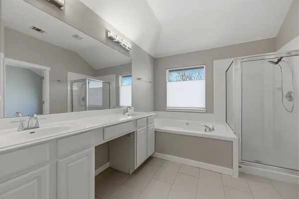 a bathroom with a double vanity sink a large mirror and a bathtub