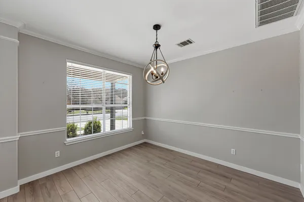 a view of an empty room with wooden floor and windows