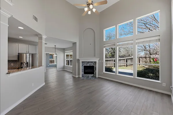 a view of a livingroom with wooden floor a fireplace window a kitchen space with refrigerator
