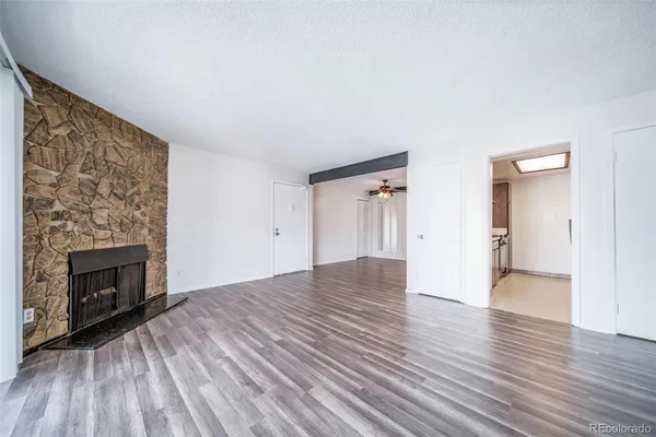 an empty room with wooden floor fireplace and windows