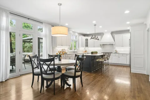 a view of a dining room and livingroom with furniture wooden floor a chandelier
