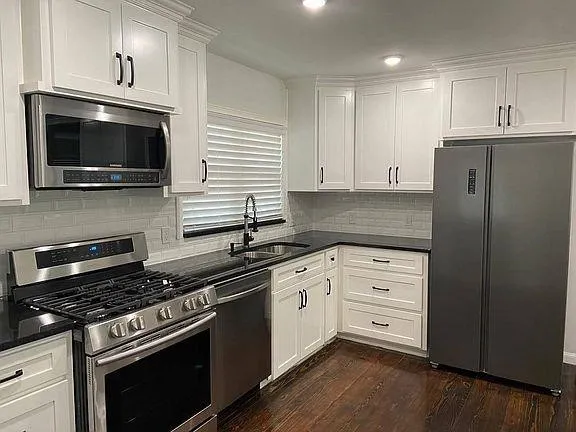 a kitchen with granite countertop cabinets stainless steel appliances and wooden floor