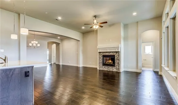 an empty room with wooden floor fireplace and windows