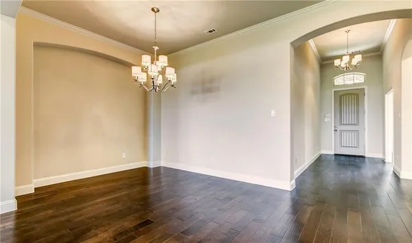 a view of a chandelier in big room with wooden floor and a chandelier