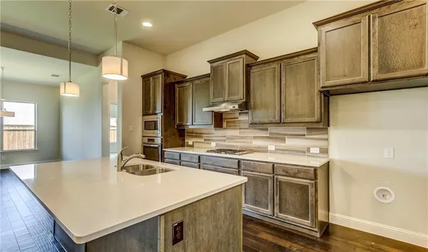 a kitchen with stainless steel appliances granite countertop a sink a stove and a refrigerator