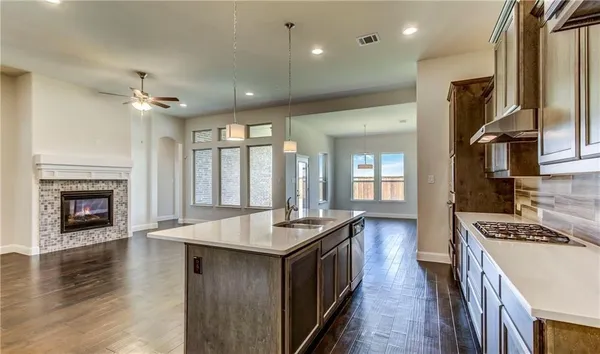 a large kitchen with kitchen island a stove a sink a refrigerator and a fireplace