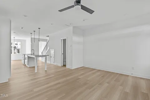 a view of an empty room with wooden floor a ceiling fan