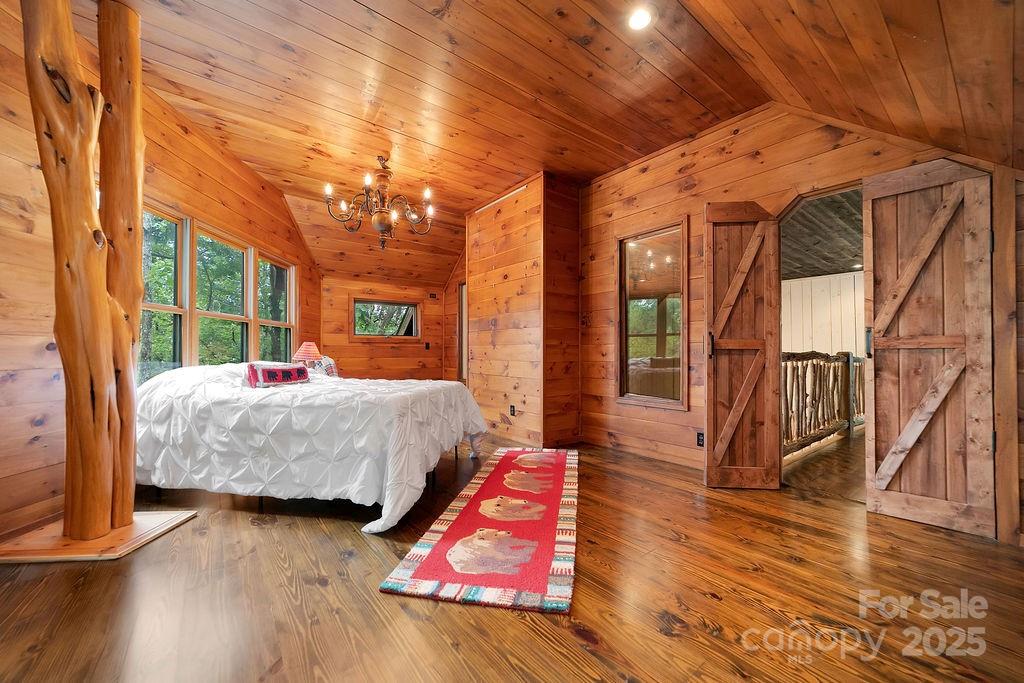 418 Sandy Lane Brevard, NC 28712 - Photo 39 of 45 a bedroom with wooden floor a bed and a chandelier