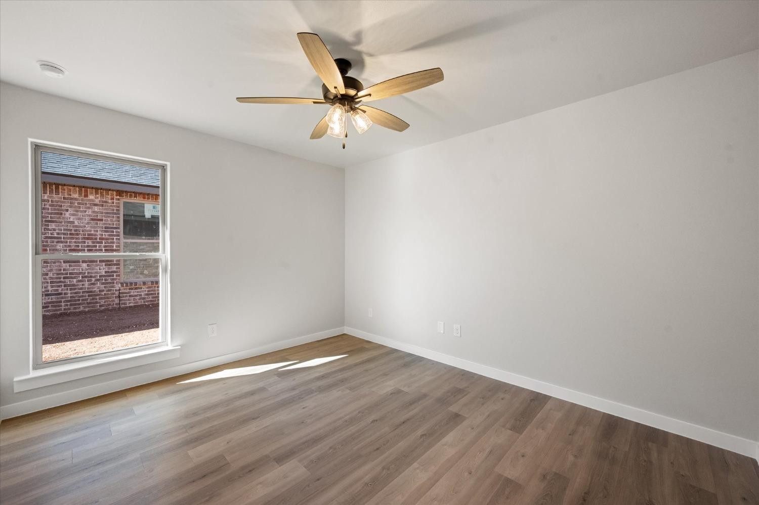 7426 30th Street Lubbock, TX 79407 - Photo 20 of 25 an empty room with wooden floor fan and windows