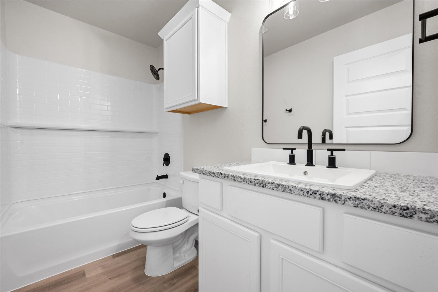 7426 30th Street Lubbock, TX 79407 - Photo 23 of 25 a bathroom with a granite countertop sink a toilet and a bathtub