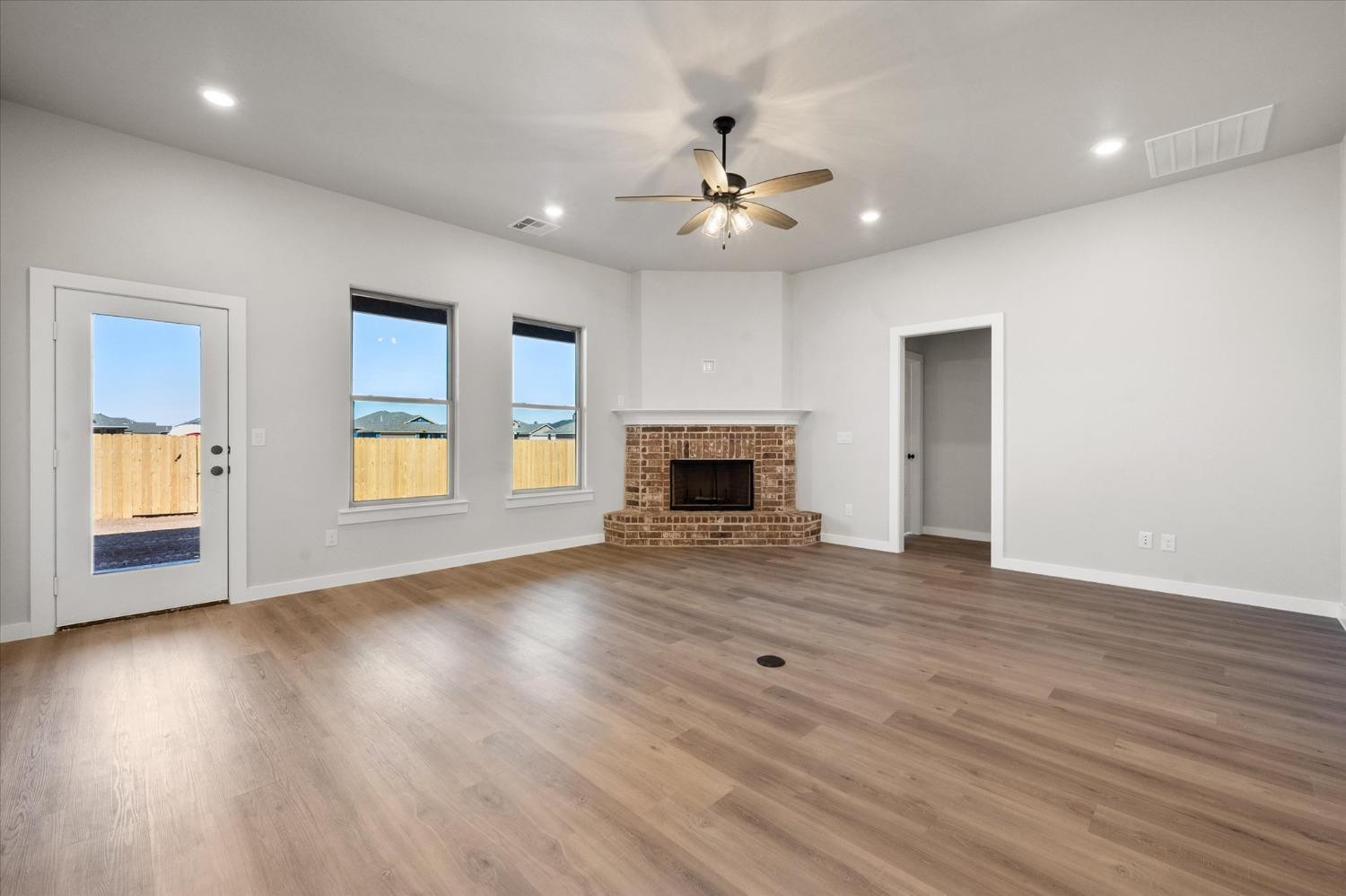 7426 30th Street Lubbock, TX 79407 - Photo 9 of 25 an empty room with wooden floor fireplace and windows