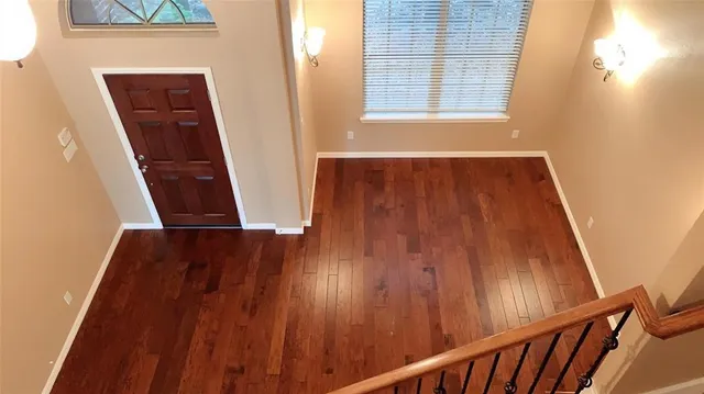 an empty room with wooden floor fireplace and windows