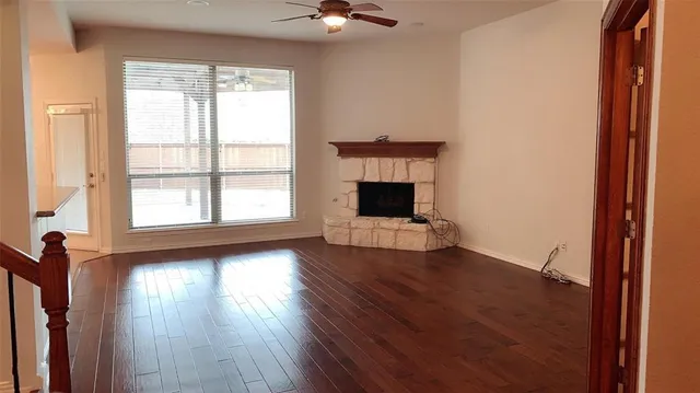 an empty room with chandelier fan and windows