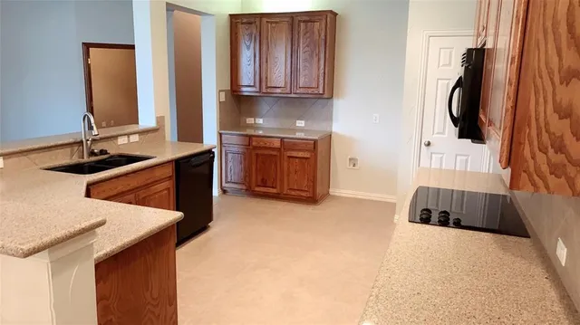 a kitchen with stainless steel appliances a sink a stove a microwave a refrigerator and cabinets