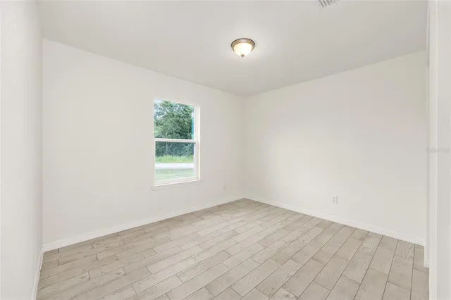 an empty room with wooden floor and window