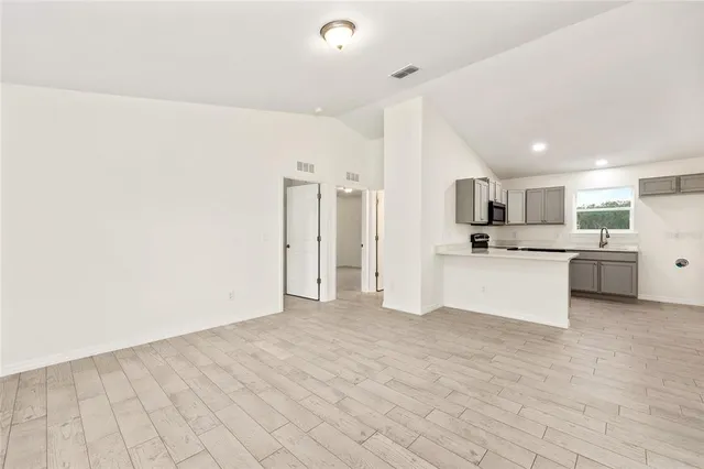 a view of kitchen with stainless steel appliances kitchen island a refrigerator sink and white cabinets