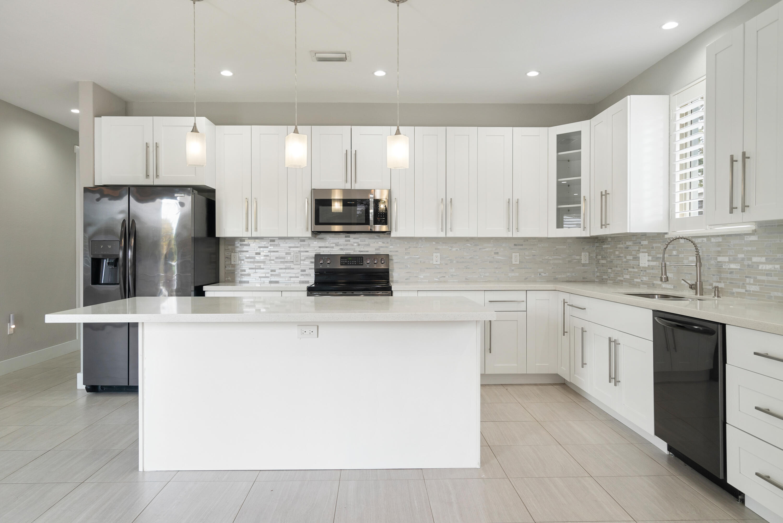 582 Boyd Drive Key Largo, FL 33037 - Photo 3 of 36 a large kitchen with stainless steel appliances kitchen island granite countertop a stove a sink a refrigerator and white cabinets