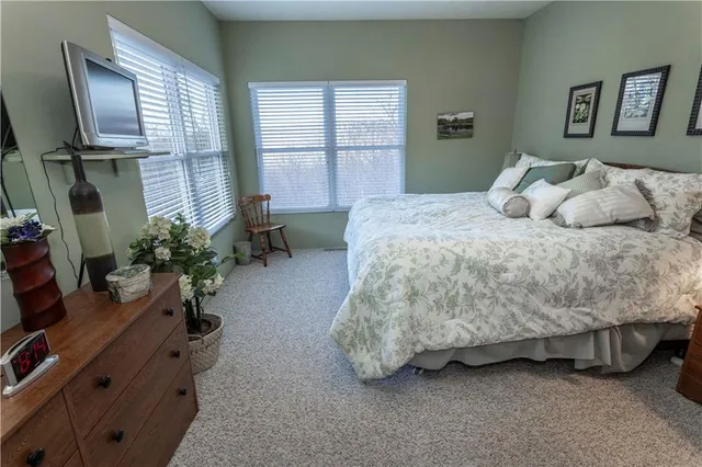 a bedroom with a bed dresser flowerpot and window