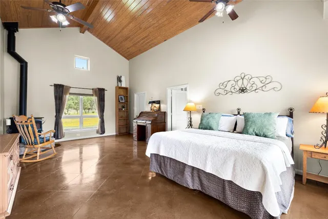 a spacious bedroom with a bed a chandelier and dresser
