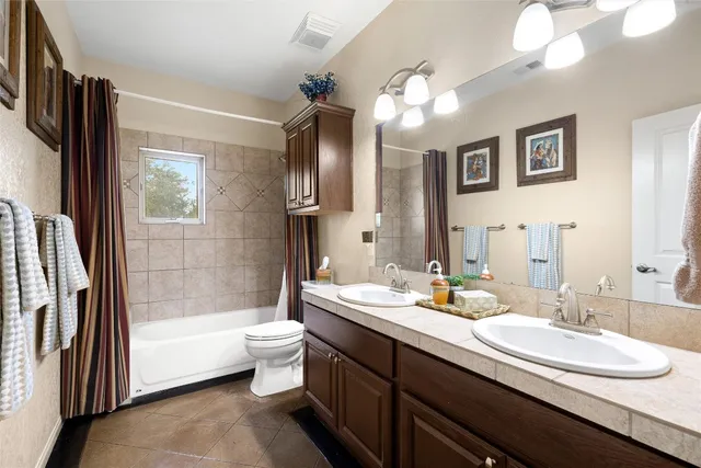 a bathroom with a double vanity sink a toilet a mirror and shower