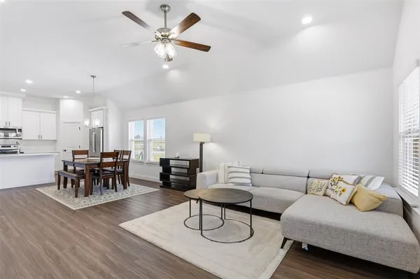 a living room with furniture and a dining table with wooden floor