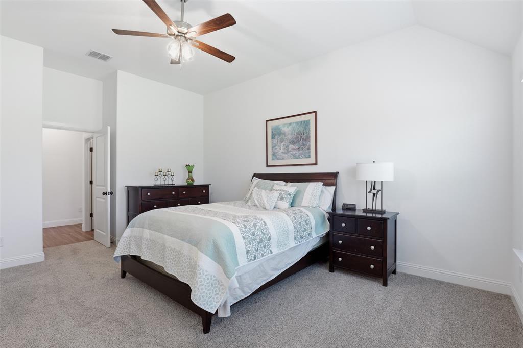 1101 Springfield Road Springtown, TX 76082 - Photo 21 of 32 a spacious bedroom with a bed and a chandelier