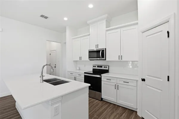 a kitchen with white cabinets and sink