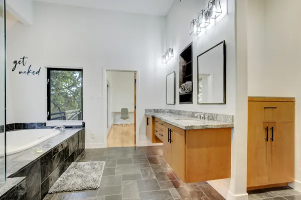 a spacious bathroom with a tub double vanity sink and a mirror