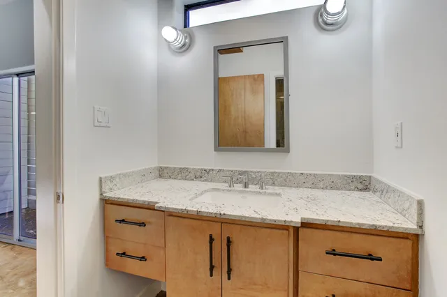 a bathroom with a granite countertop sink and a mirror