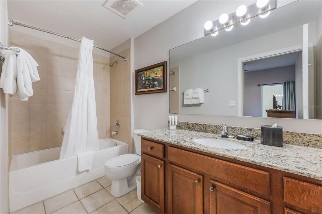 8774 Worldquest Boulevard, Unit 7404 Orlando, FL 32821 - Photo 22 of 55 a bathroom with a granite countertop sink a toilet and shower