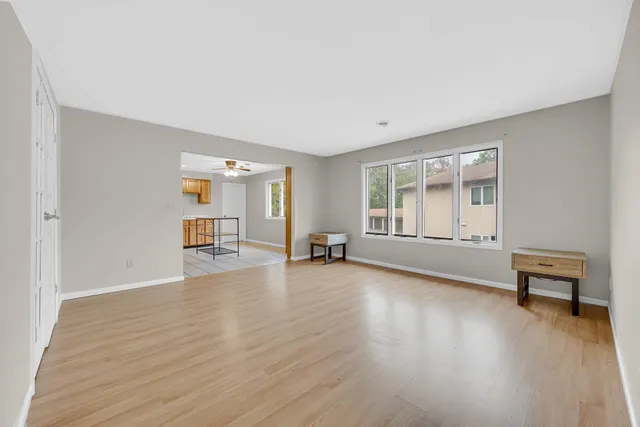 a view of an empty room with a window and wooden floor