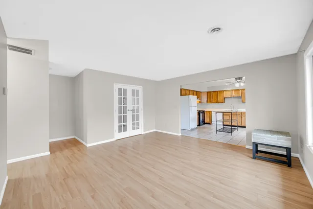a view of empty room with wooden floor and fan
