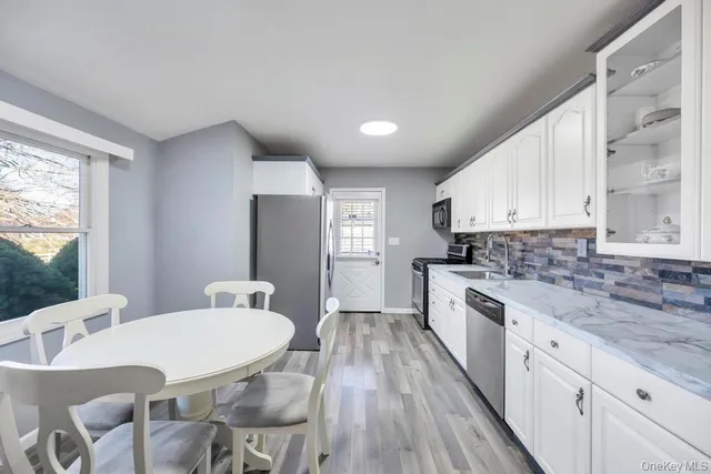 a kitchen with stainless steel appliances a dining table chairs and a large window