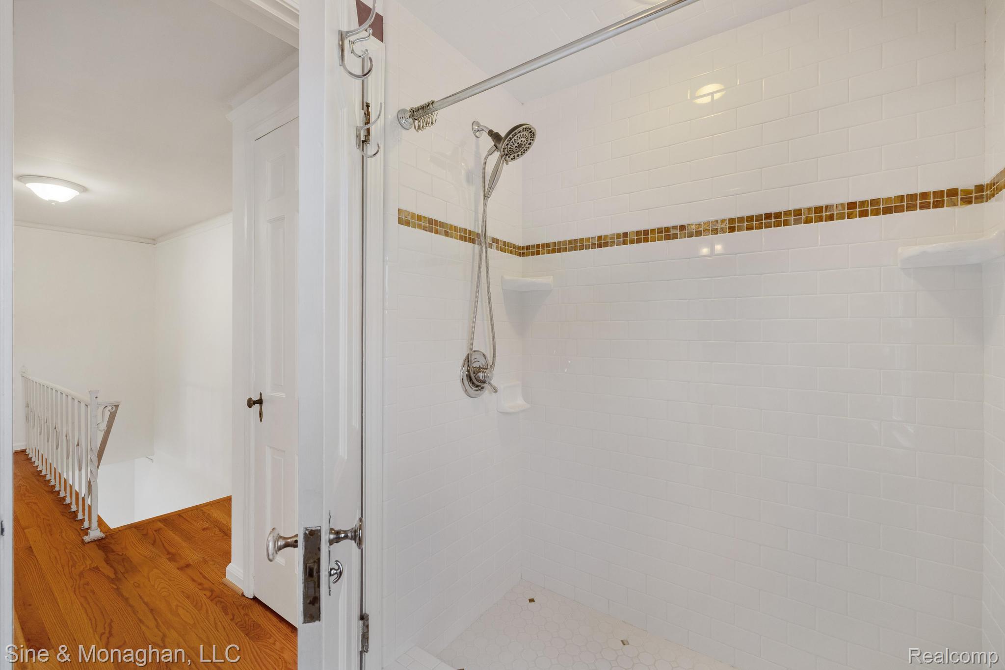 679 Neff Road Grosse Pointe, MI 48230 - Photo 33 of 78 White subway tile shower with a decorative mosaic band and two built-in corner shelves
