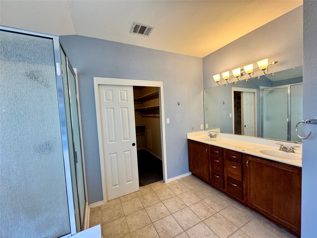 14605 Staked Plains Loop Austin, TX 78717 - Photo 12 of 30 Full bath featuring a shower stall, a walk in closet, double vanity, and light tile patterned floors
