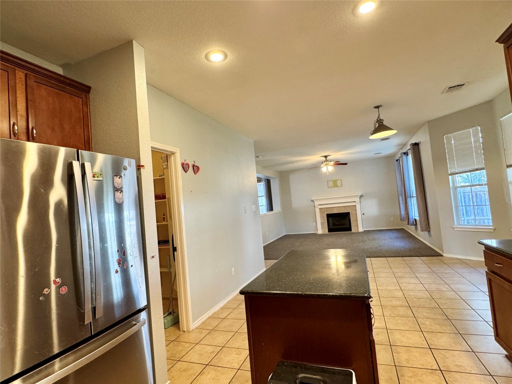 14605 Staked Plains Loop Austin, TX 78717 - Photo 28 of 30 Kitchen with freestanding refrigerator, open floor plan, a tiled fireplace, light tile patterned floors, and ceiling fan