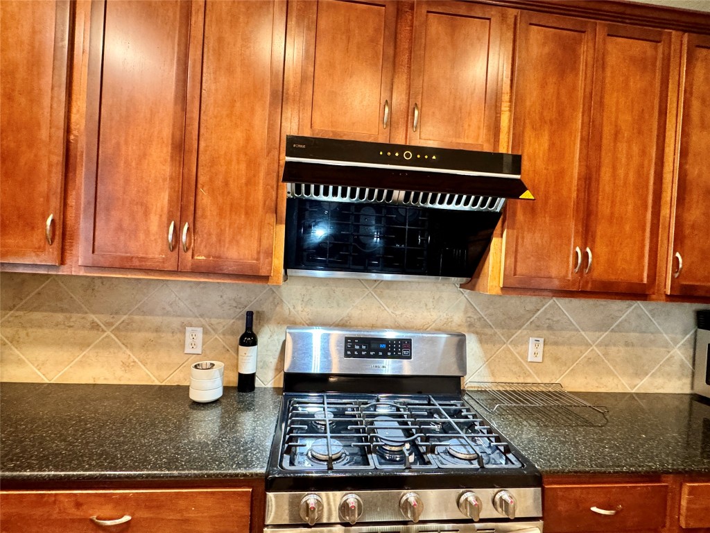 14605 Staked Plains Loop Austin, TX 78717 - Photo 23 of 30 Kitchen with stainless steel gas range, brown cabinets, and dark stone counters