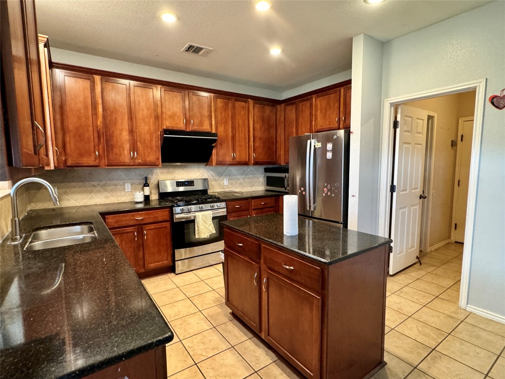 14605 Staked Plains Loop Austin, TX 78717 - Photo 4 of 30 Kitchen with appliances with stainless steel finishes, a center island, dark stone counters, range hood, and recessed lighting
