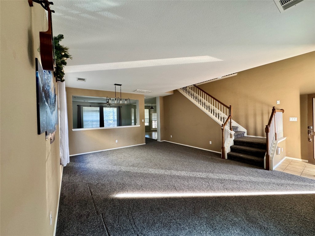 14605 Staked Plains Loop Austin, TX 78717 - Photo 5 of 30 Unfurnished living room with carpet, stairway, and a textured ceiling